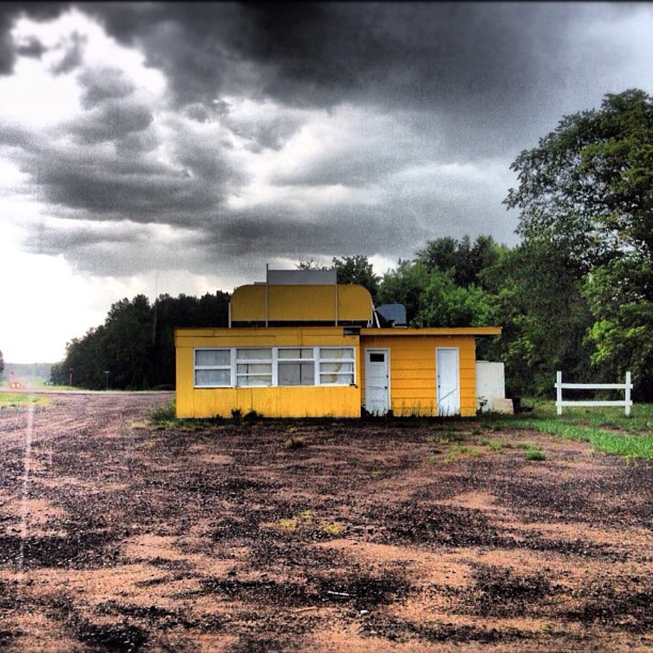 Yellow roadside stand under a storm sky