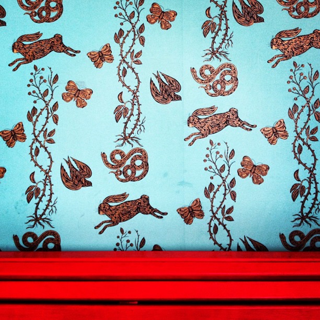 Hare and snake wallpaper above a red bench