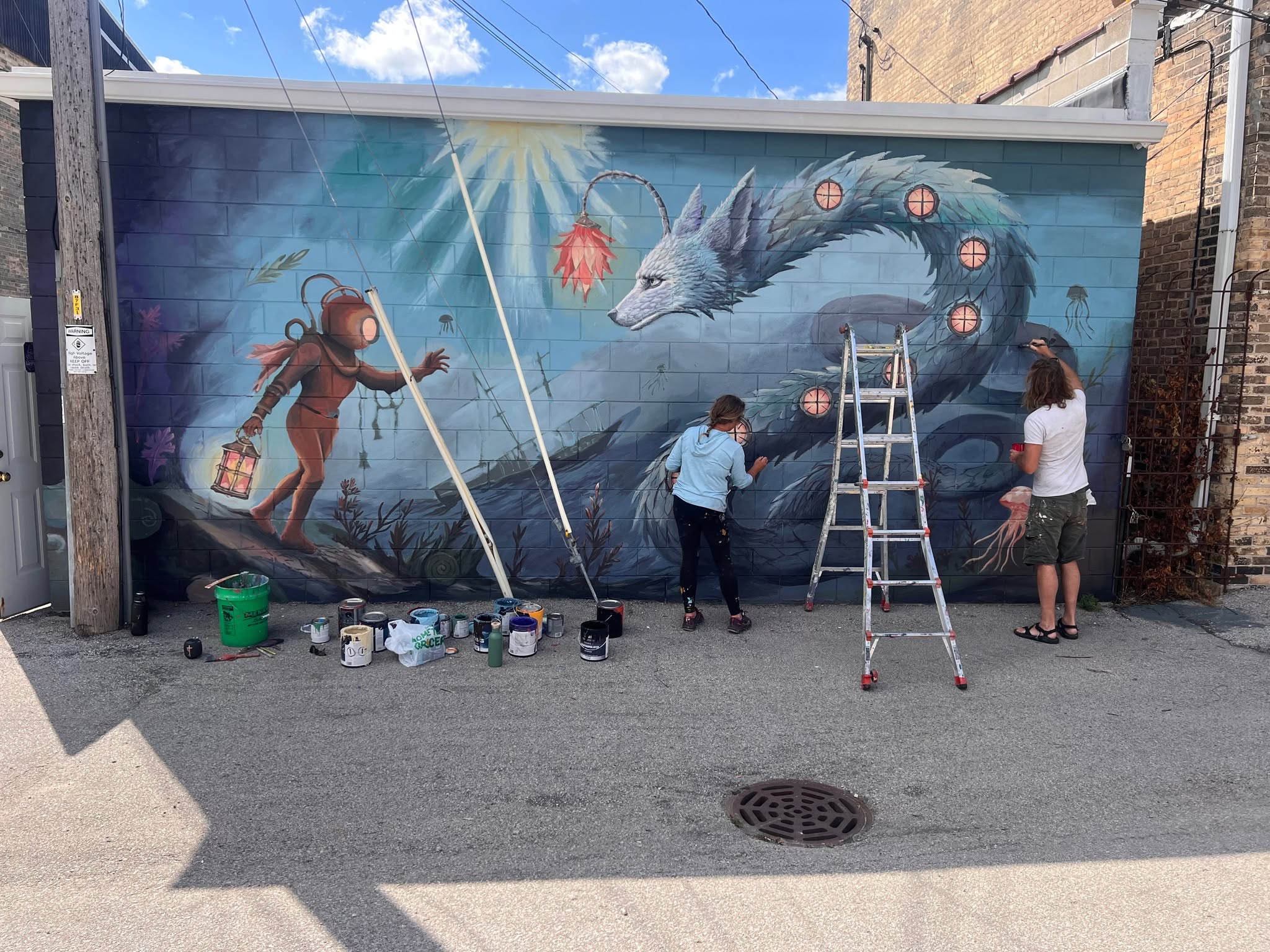 Painting day in the alley, both hands on the wall.
