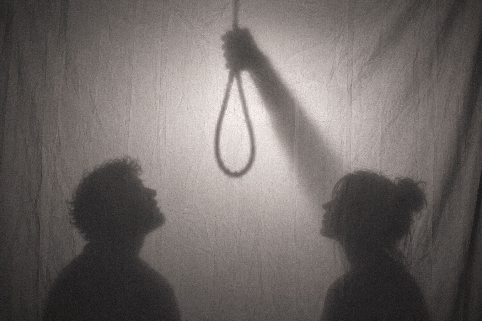 Studio tableau: the noose rendered only as cast shadow, because the rope itself has been gone for a century and a half. Two figures stand in for the six thousand who came to watch.