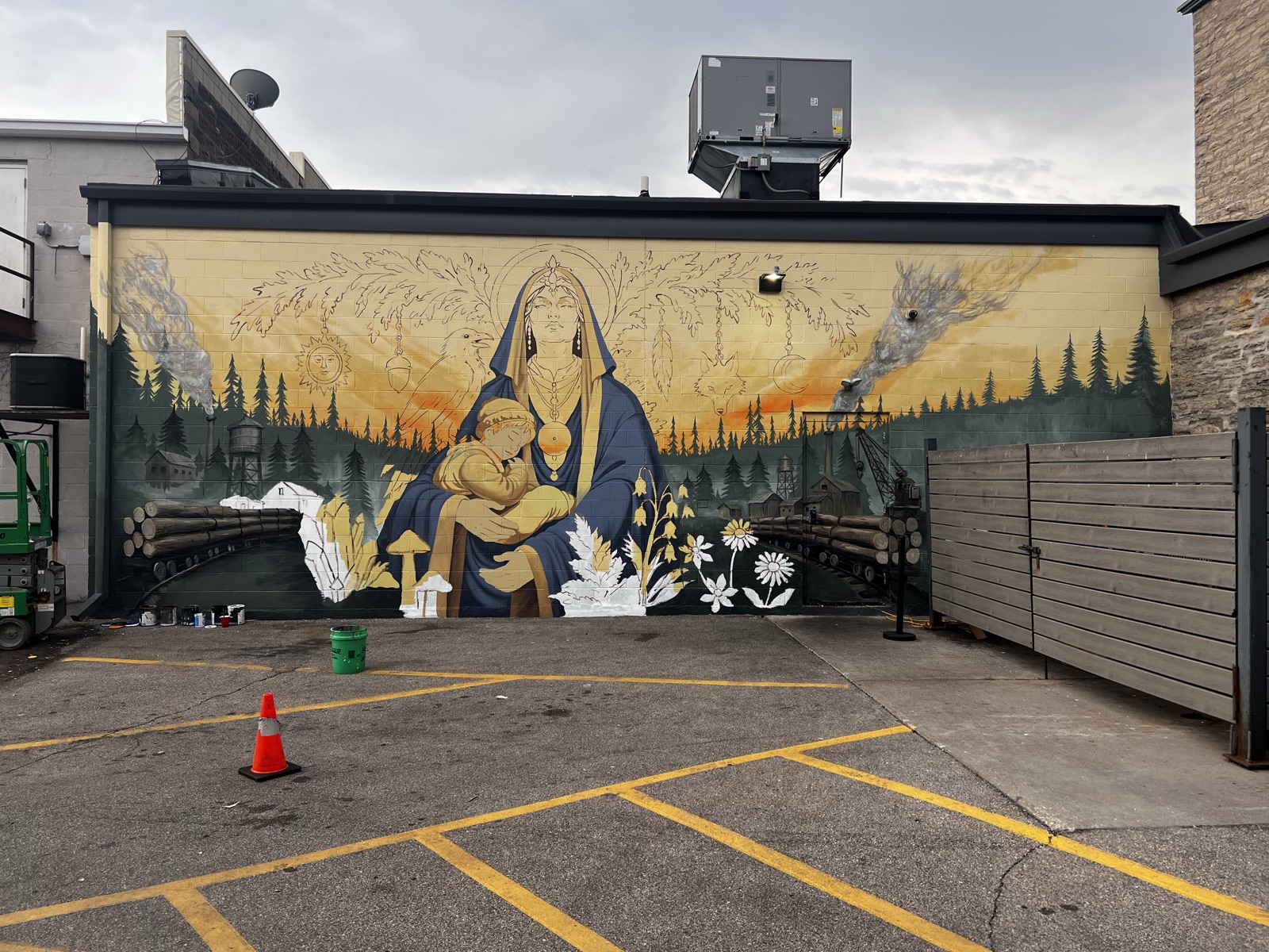 The nearly finished mural, full color across the whole wall, mill town working on both sides of the Madonna