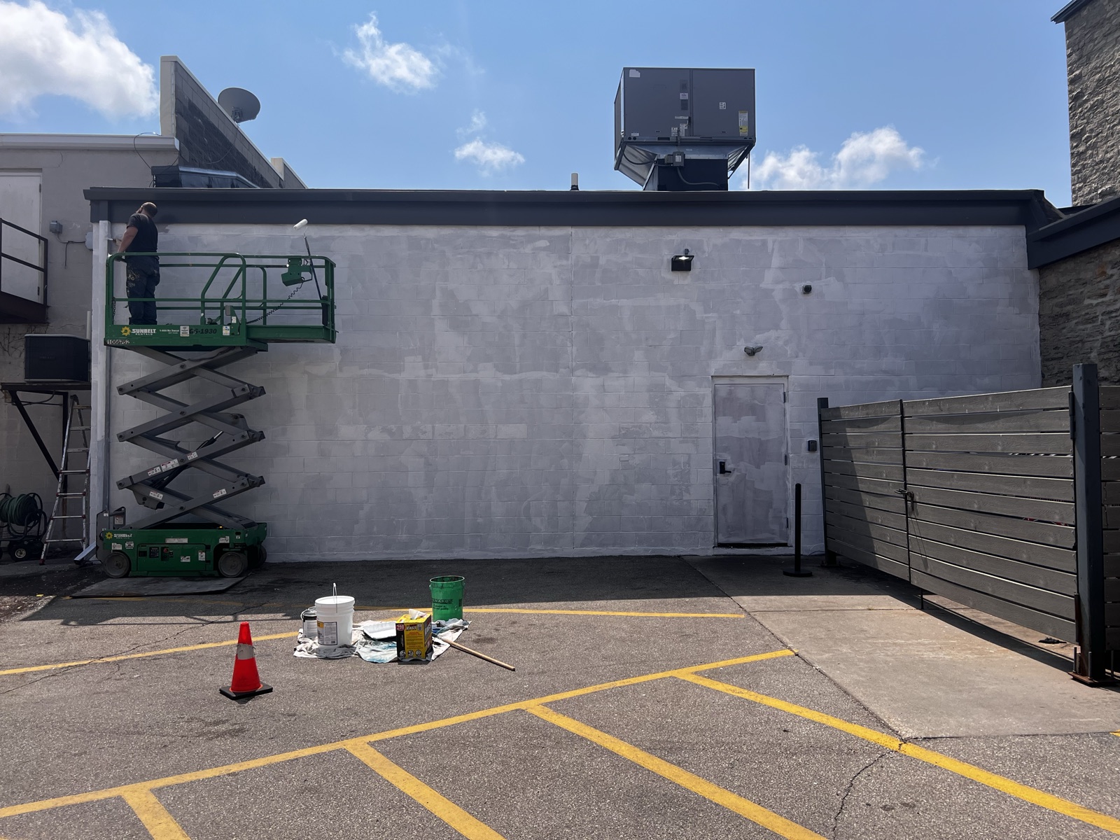 The blank primed cinderblock wall with a scissor lift, before any paint