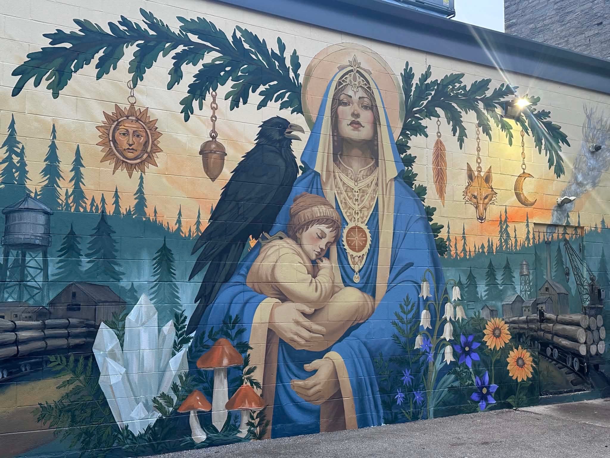 The finished Mill Madonnas mural seen at an angle along the wall, evening light catching the paint